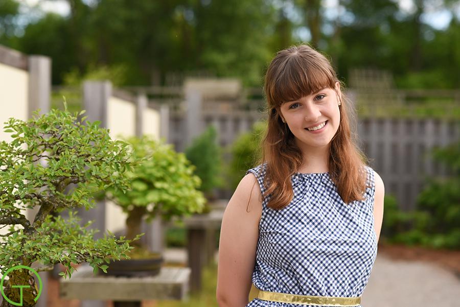 A high school senior poses amongst the bonsai tree collection at Matthaei Botanical Gardens for her senior session