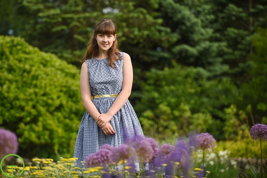 A high school senior poses near colorful flowers at Matthaei Botanical Gardens for her senior session in ann arbor