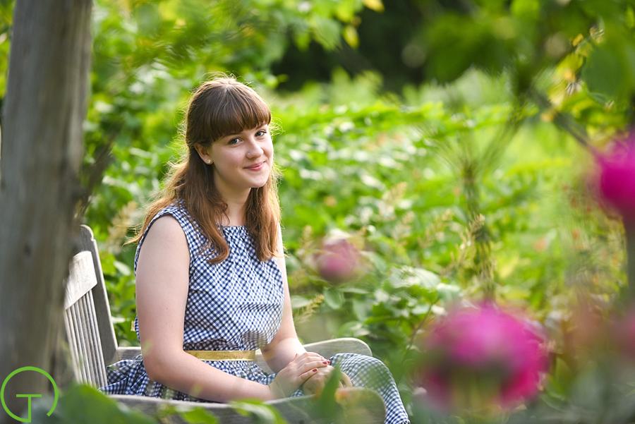 A high school senior is surrounded by lush green plants during her Matthaei Botanical Gardens senior session