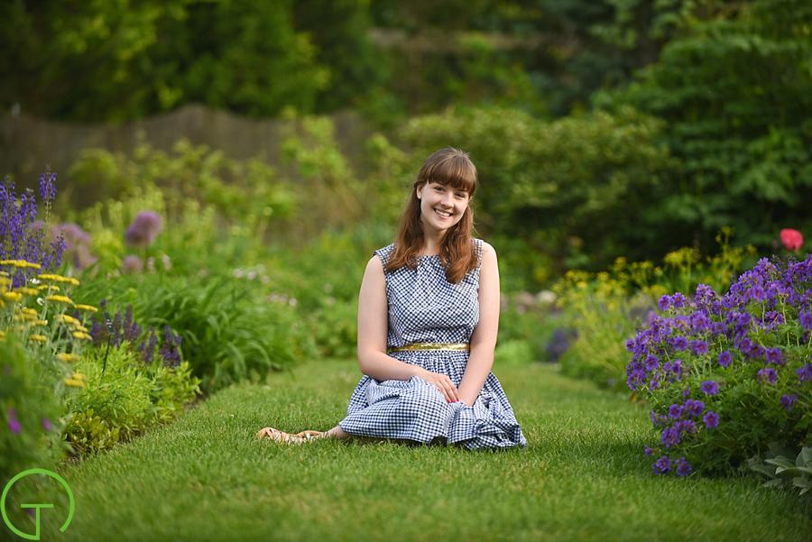A teenager poses near colorful flowers at Matthaei Botanical Gardens for her senior session