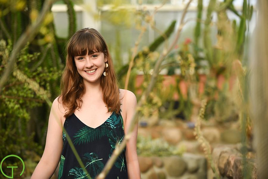 A high school senior poses in the Conservatory at A high school senior poses amongst the bonsai tree collection at Matthaei Botanical Gardens for her ann arbor senior session
